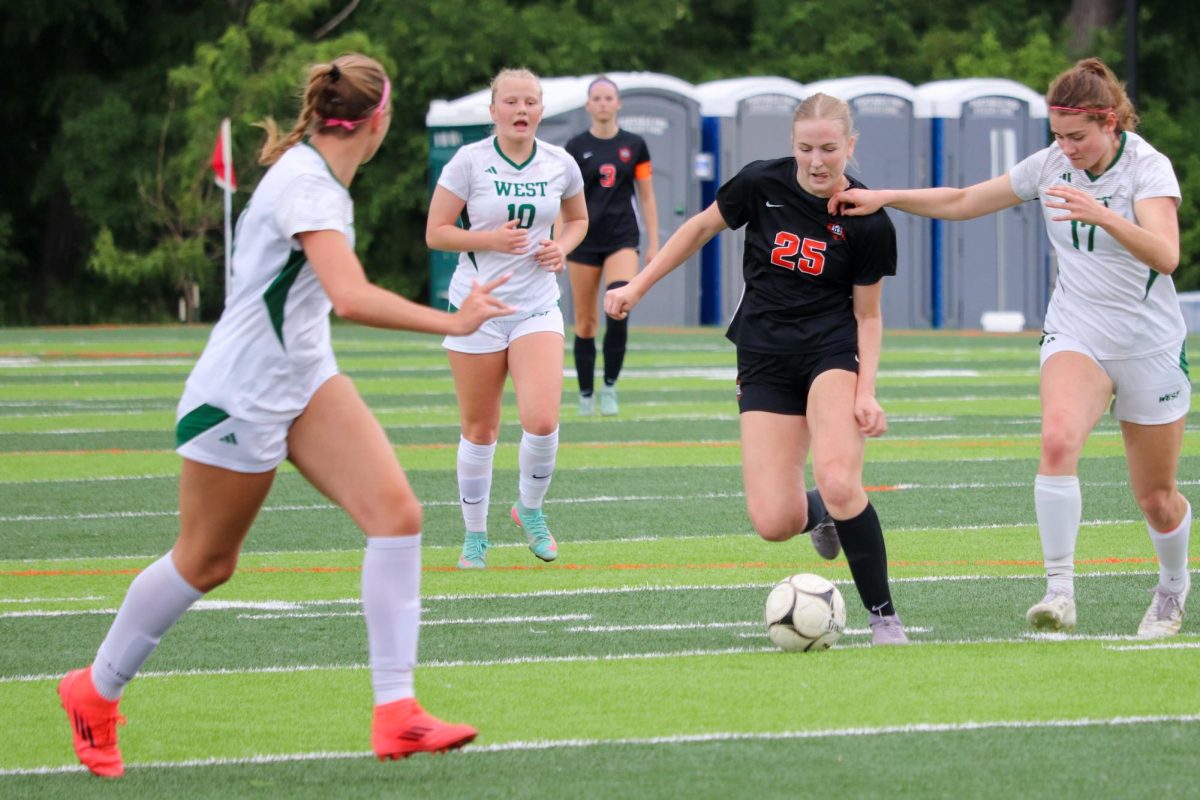 Kiersten Hinson (25) dribbles past Trojan defender Vera Tanas (17).