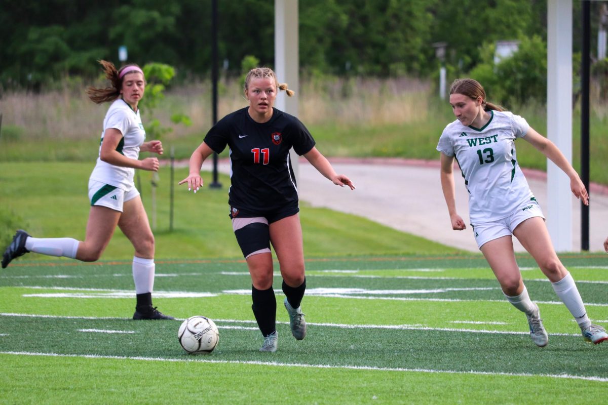 Madisyn Tucker (11) of Ames splits two Iowa City West defenders.