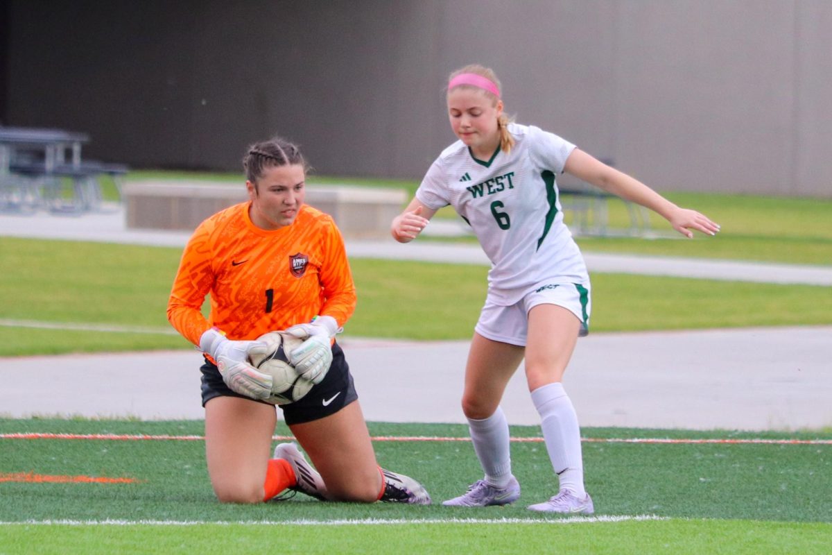 Elizabeth Lehmkuhl (1) of Ames makes one of her seven saves. On her right is Iowa City West’s Sophia Oulman (6).