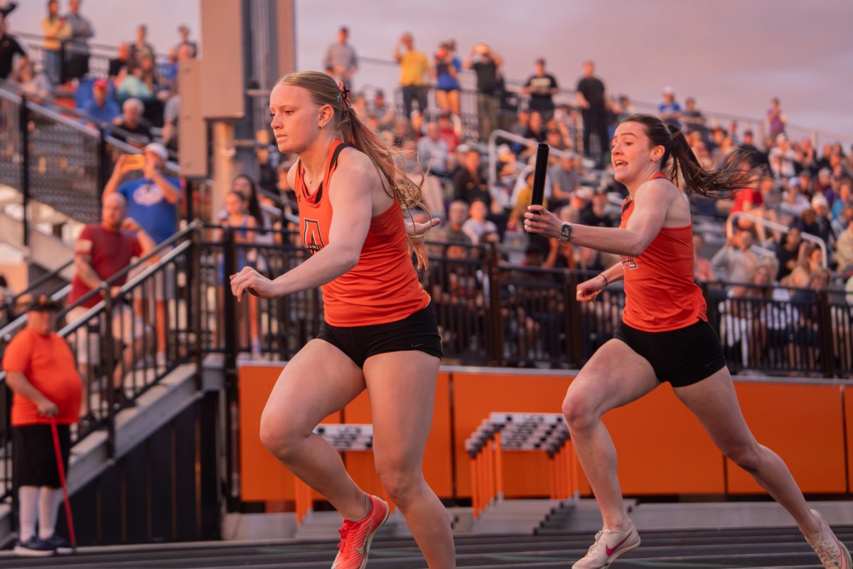 Ames’ Natalya Deardorff hands off the baton to Edyn Cowles in the 4x200-meter relay, helping the Blue Standard qualifying team finish in 1:43.19 at Ames High School on Tuesday.